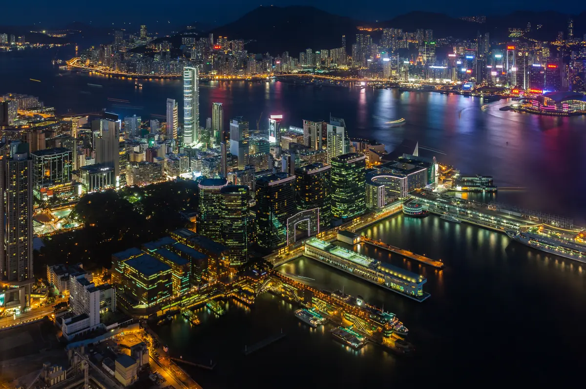 Victoria Harbour at blue hour from sky100, on the 100th floor of the International Commerce Centre, the tower the Ritz-Carlton sits in: the lit Tsim Sha Tsui waterfront below, the harbour in the middle and the Hong Kong Island skyline glittering across the water.