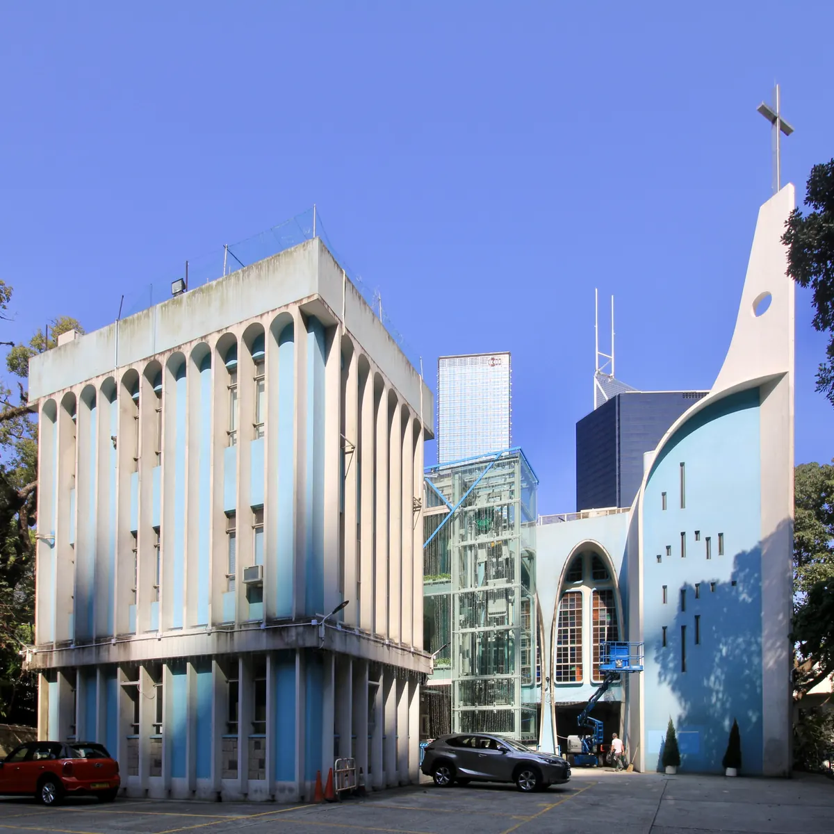 St Joseph's Church on Garden Road in Central: a modernist building in pale blue and white, with a curving white tower and cross, under a deep blue sky.